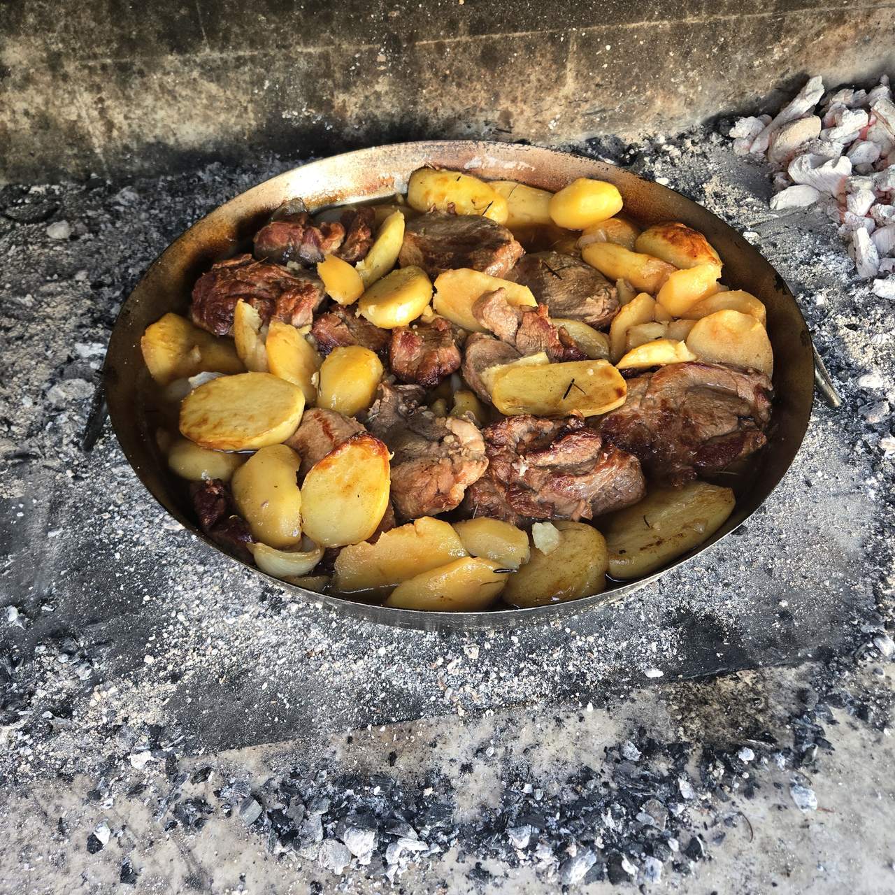 Peka with meat and potatoes, slow-cooked under the bell over embers